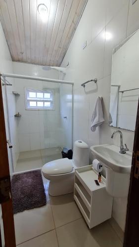 a white bathroom with a toilet and a sink at Casa Paúba 80m do Mar in Maresias