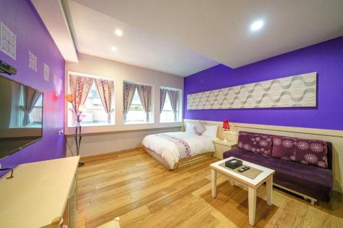 a purple bedroom with a bed and a couch at Honey House in Luodong