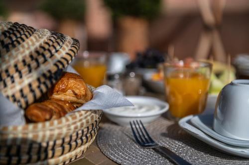 a table topped with a basket of bread and orange juice at Riad Altair in Marrakech