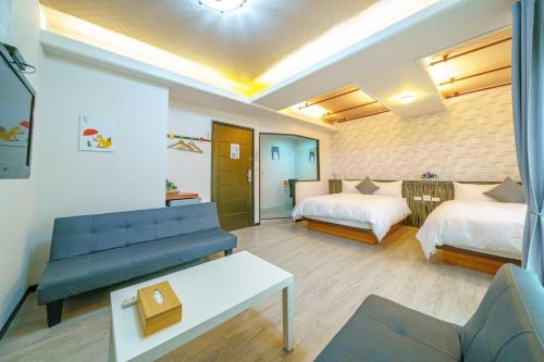 a hotel room with a couch and two beds at Honey House in Luodong