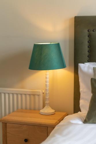 a green lamp on a night stand next to a bed at Cliftonville Hotel in Cromer