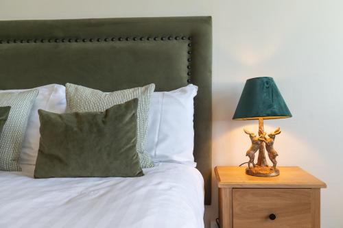 a bed with a green lamp on a wooden night stand at Cliftonville Hotel in Cromer