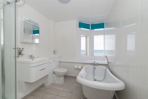 a white bathroom with a sink and a tub and a toilet at Cliftonville Hotel in Cromer