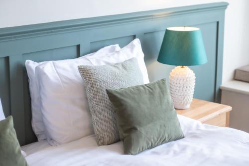 a bed with white pillows and a green lamp on a table at Cliftonville Hotel in Cromer