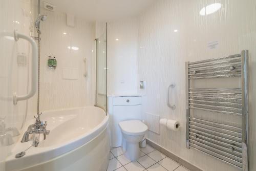 a bathroom with a tub and a toilet and a sink at Cliftonville Hotel in Cromer