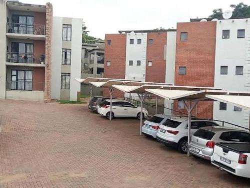 a row of cars parked in a parking lot next to buildings at Luxuries Penthouse in Nelspruit