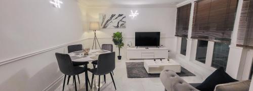 uma sala de estar com uma mesa e cadeiras e uma televisão em Stunning 2 bedroom apartment in Canary Wharf - Morland Apartments em Londres