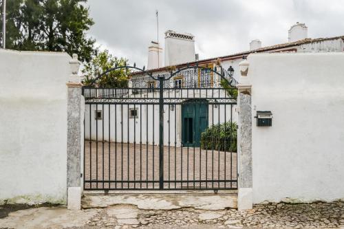 a gate to a white building with a blue door at Eighteen21 Houses - Casa dos Condes in Cano