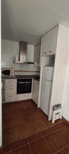 cocina con armarios blancos y suelo de baldosa en Ca Victor II en Arnes