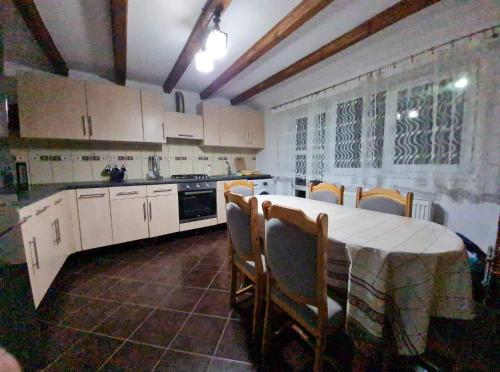 uma cozinha com mesa e cadeiras e uma cozinha com armários brancos em Casa Ostrov em Călimăneşti