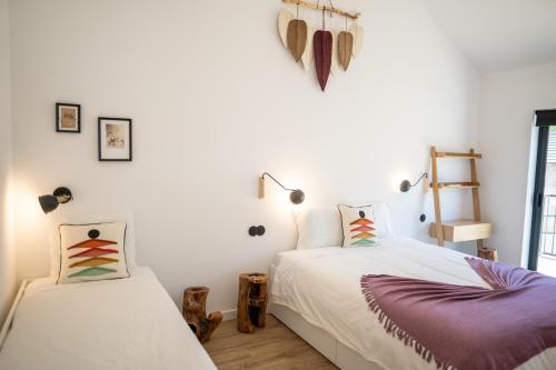 2 camas en una habitación con paredes blancas en Montesinho Eco-Resort, en Bragança