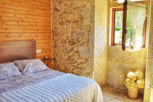 1 dormitorio con cama y pared de piedra en Casa dos Amos en Costa da Morte. A Coruña, en Ponteceso