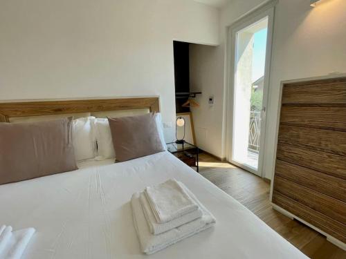 een slaapkamer met een wit bed en 2 handdoeken bij La Petite Maison in Colombaro