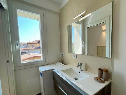 een badkamer met een wastafel, een spiegel en een raam bij La Petite Maison in Colombaro