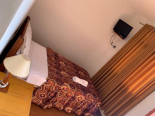 małe łóżko w małym pokoju z łóżkiem sidx sidx sidx w obiekcie Hostal El Amigo w mieście Paracas