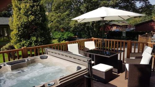 a hot tub on a deck with an umbrella at 48 Pony Meadow - White Cross Bay in Windermere