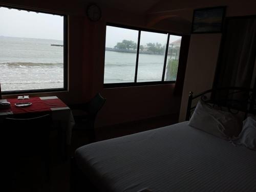 sypialnia z 2 oknami i łóżkiem z widokiem na ocean w obiekcie Goan Delicacy Guest House w mieście Panaji