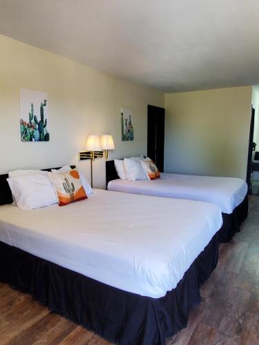 two beds in a hotel room with white sheets at Cactus Inn and Suites in Mountain Grove