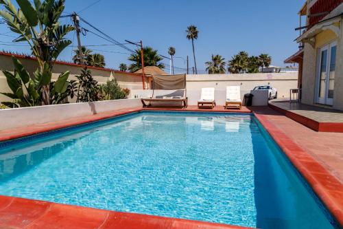 a swimming pool with two chairs in a house at Playa Hermosa Inn at the beach in Ensenada