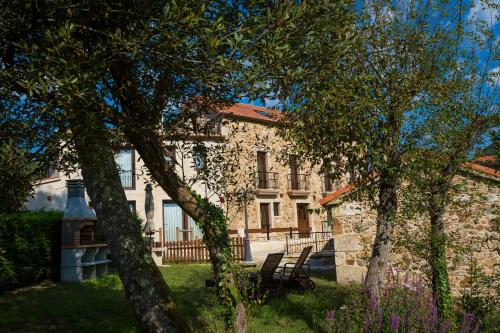 a stone house with trees in front of it at Pensión *** O Relax do Río in Muxia