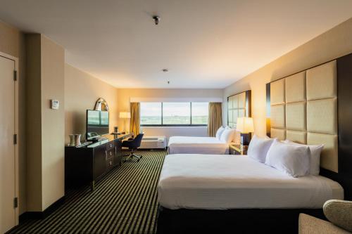 a hotel room with two beds and a desk at APA Hotel Woodbridge in Iselin