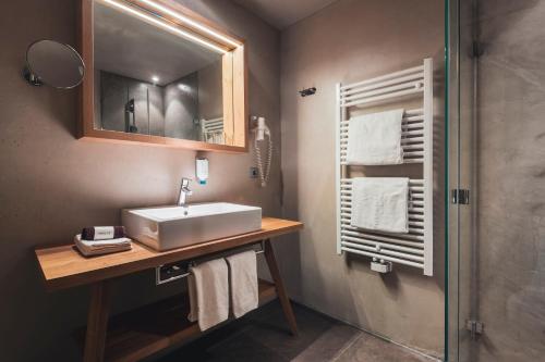 a bathroom with a sink and a mirror and a shower at Hotel Arlara in Corvara in Badia