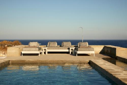 a pool with two beds and chairs next to the ocean at Santa Irini Retreat in Therasia