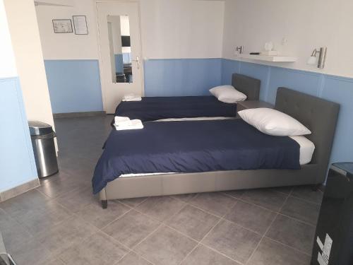 two beds in a room with blue walls at Hotel Geoffroy Marie Opéra in Paris