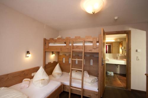 a room with two bunk beds and a bathroom at Kinderhotel Laderhof in Ladis