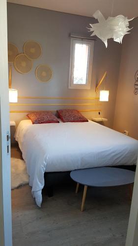 een slaapkamer met een groot wit bed en een raam bij Gîte T2 A l'orée d'Angers in Avrillé