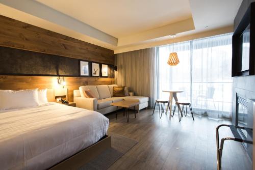 a hotel room with a bed and a couch and a table at Espace 4 Saisons in Magog-Orford