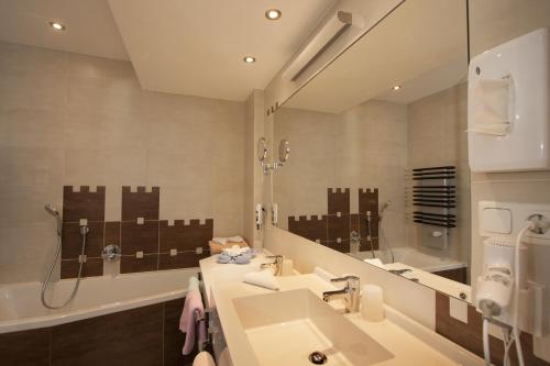 a bathroom with a sink and a large mirror at Kinderhotel Laderhof in Ladis