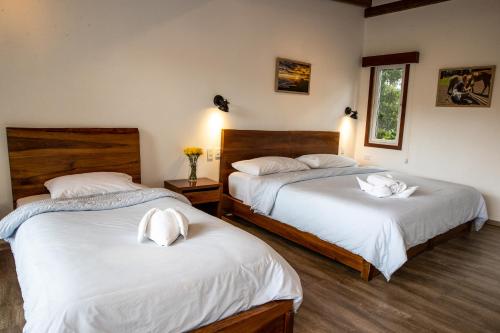 a bedroom with two beds with white sheets at Hosteria Papagayo Cotopaxi in Machachi
