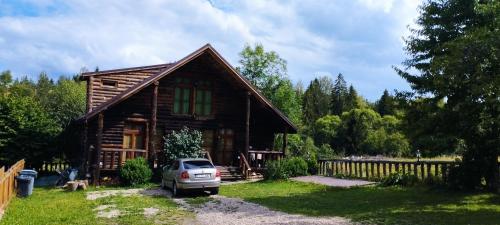 un'auto parcheggiata di fronte a una baita di tronchi di Cabana Belis Dealu Negru a Beliş