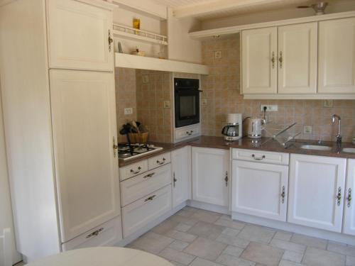 une cuisine blanche avec des armoires et des appareils blancs dans l'établissement Les Jardins des 3 Provinces- Gîte, à Montcharvot