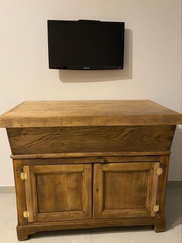 a wooden table with a television on a wall at Gîte à la ferme chez Félix et Marie-Ca in Vallecalle
