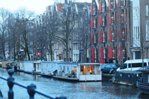 
a city street filled with lots of parked boats at Pantheos Top Houseboat in Amsterdam
