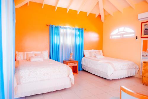 two beds in a room with orange walls at Villa Encantada Aruba in Noord