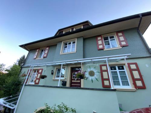 a house with red shutters and a sunflower on the window at Haus Silberdistel in Todtmoos