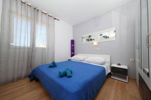 um quarto com uma cama azul e uma janela em Apartman Goga em Tučepi