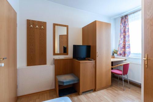 a room with a desk with a television and a chair at Hotel am Römerplatz in Ulm