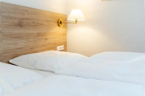 a bed with a white pillow and a lamp at Hotel am Römerplatz in Ulm