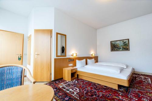 ein Schlafzimmer mit einem Bett und einem Tisch in einem Zimmer in der Unterkunft Hotel am Römerplatz in Ulm