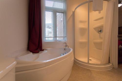 a white bathroom with a tub and a shower at Acacias Bed & Breakfast in Quebec City