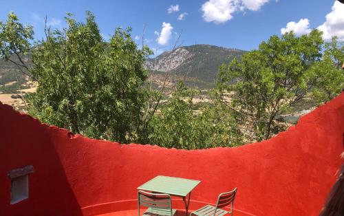 una mesa y sillas en un patio con una pared roja en La Tour des Baronnies à la Porte de l eau, en Saint-Auban-sur-Ouvèze