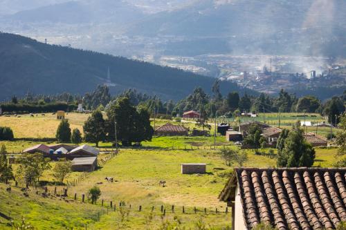 un petit village dans un champ verdoyant avec une montagne dans l'établissement Posada Rural - La Isabela, à Tópaga