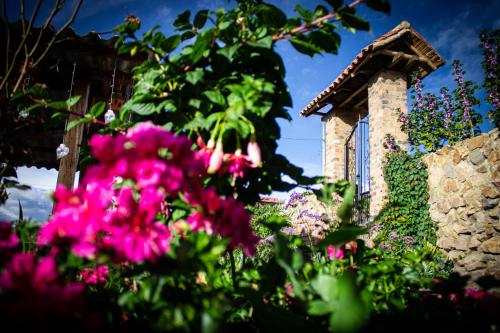 a garden with pink flowers and a stone building at Posada Rural - La Isabela in Tópaga