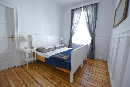 a white bedroom with a bed and a window at Wilhelmstadt Apartment 60m - PARKING in Toruń