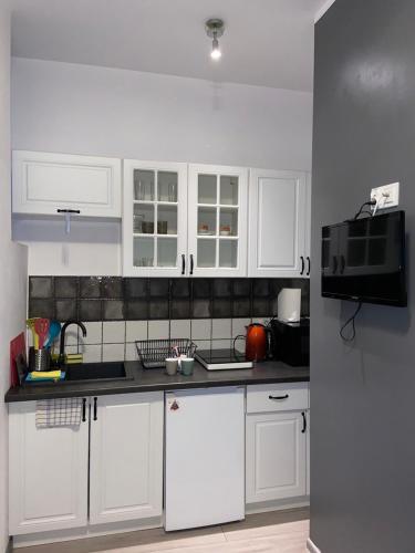 une cuisine avec des placards blancs et un comptoir noir dans l'établissement Apartament Grunwaldzka, à Bydgoszcz