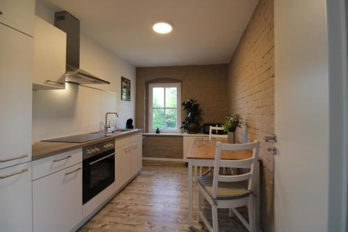 a kitchen with white cabinets and a wooden table at Ferienwohnung in herrlicher Teichlandschaft in Caminau